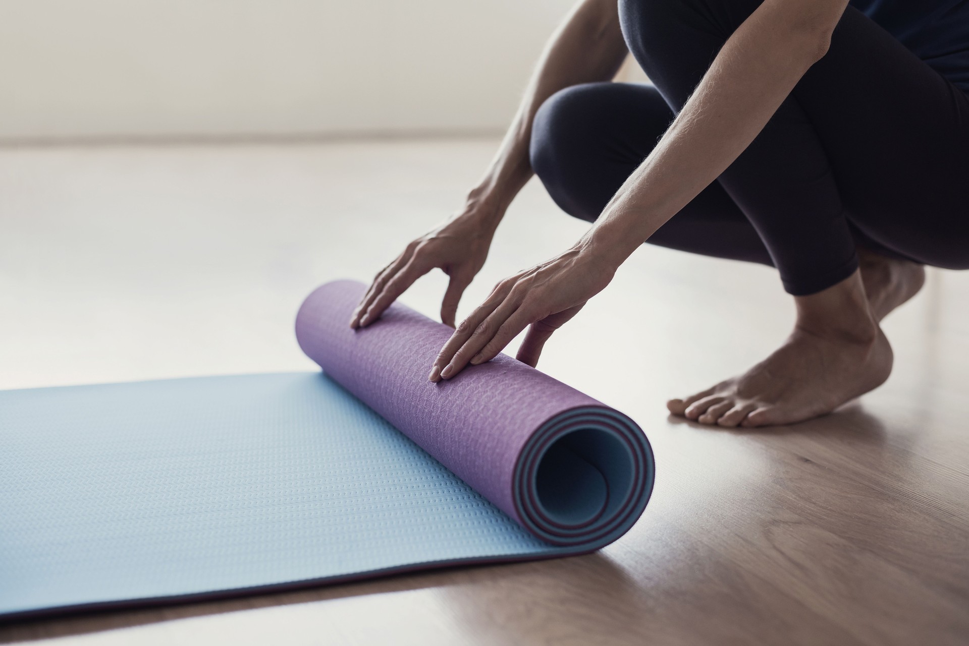 Woman rolling up exercise mat and preparing doing yoga or fitness